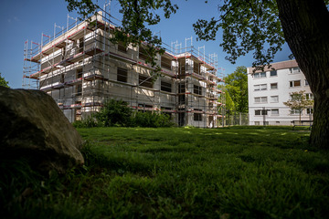 Mehrfamilienhaus mit Gerüst auf einer grünen Wiese